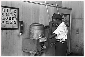 Pictured: An African American man drinks from a water cooler in 1939. Photo by Russell Lee, United States Library of Congress.